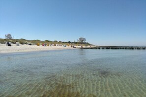 A beach with clear shallow water, a sandy shore, and a row of tents. - Holiday apartment with 2 bedrooms (Zingst)