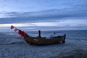 Ein hölzernes Boot mit der Aufschrift 'KOL 10' am sandigen Strand.