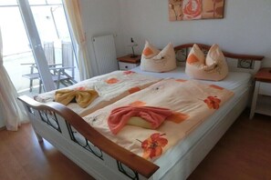 A double bed with floral bedding, two bedside tables, a chair, and a radiator. - Holiday apartment in Baabe with swimming pool (Baabe)