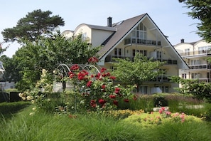 A two-story house with a balcony, surrounded by a garden with various plants and flowers. - Holiday apartment in Baabe with swimming pool (Baabe)