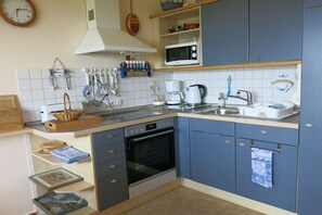 Eine Küche mit Mikrowelle, Backofen, Spüle und diversen Kochutensilien.