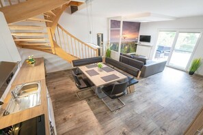 A modern kitchen with a built-in oven, a dining area with a table and chairs, a staircase, and a large window with a view. - in the Martina apartment building (Mörbisch)