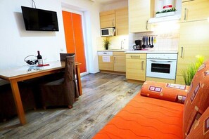 A compact kitchen with a microwave, stove, and a dining area with a table and chairs. - in the Martina apartment building (Mörbisch)