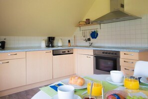 Eine Küche mit Essbereich, ausgestattet mit einer Kaffeemaschine, einem Toaster, einem Backofen und verschiedenen Küchengeräten.
