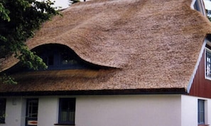 Ein Haus mit einem Strohdach und einer weißen Fassade.