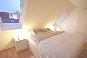 A bedroom with a skylight, a bedside table with a lamp, a bed with pillows, and a nightstand. - Holiday home in Zingst with swimming pool (Zingst)