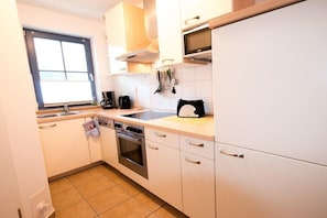 A compact kitchen with white cabinets, a microwave, a coffee maker, and a toaster. - Holiday home in Zingst with swimming pool (Zingst)