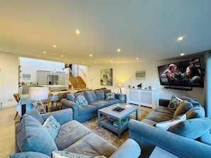 Ein modernes Wohnzimmer mit einer Sofagarnitur, einem Couchtisch und einem an der Wand befestigten Fernseher.