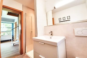 Ein modernes Badezimmer mit einem weißen Waschbecken, einem Spiegel darüber und einer Tür, die auf einen Balkon führt.