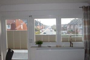 Ein Zimmer mit großem Fenster und Blick auf eine Wohnstraße.