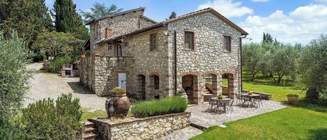 A stone house with a patio, outdoor seating, and a garden.