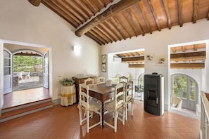 A dining area with a wooden table and chairs, a black grill, and a view through the windows. - Your Authentic Chianti Escape in San Sano (San Sano)