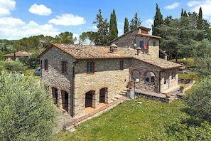 A stone house with a tiled roof, arched windows, and a small porch. - Your Authentic Chianti Escape in San Sano (San Sano)