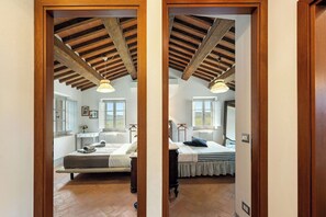 A bedroom with a wooden ceiling, a bed, a bedside table, a window, and a radiator. - Your Authentic Chianti Escape in San Sano (San Sano)