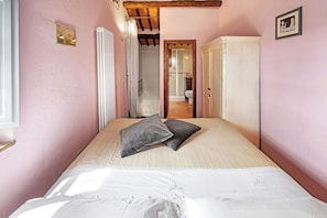 A bedroom with a bed, a wardrobe, a radiator, and a door leading to a bathroom. - Your Authentic Chianti Escape in San Sano (San Sano)