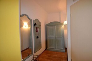 Ein Flur mit Spiegel, Kleiderschrank und Lampe.