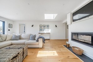 Ein modernes Wohnzimmer mit einer Couch, einem Kamin und einem Oberlicht.