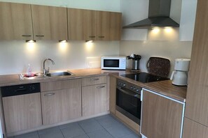 Eine moderne Küche mit Holzausstattung, einem Geschirrspüler, einer Mikrowelle, einem Backofen und einer Kaffeemaschine.
