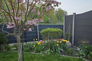 A garden with a tree, various plants, and a fence. - Ecki's holiday home "Komm An de Bäk" (Alt Schönau)