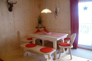 Ein Holzinnenraum mit Tisch, Bänken und Stühlen, einer Hängeleuchte und einem Wanddekor.