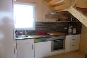 Eine kleine Küche mit eingebautem Geschirrspüler, Backofen und Fenster.