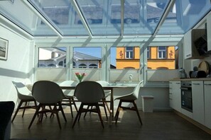 Una cocina moderna con tragaluz, armarios blancos y una zona de comedor con sillas.