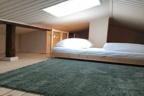 Ein Schlafzimmer im Loft-Stil mit Dachfenster, einem Bett und einem grünen Teppich.
