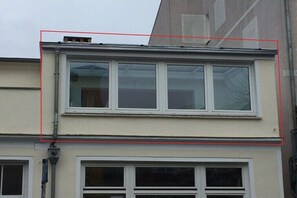 Un edificio con techo plano, varias ventanas y una chimenea visible.
