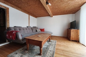 Ein Wohnzimmer mit einer Couch, einem Holztisch, einem Fernseher und einer Holzkommode.