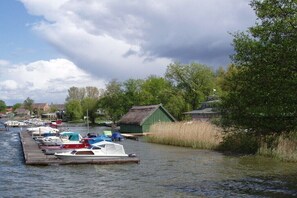 A calm river with boats docked along the pier, surrounded by greenery and buildings. - Holiday apartment with 1 bedroom (Neustrelitz O.T. Klein Trebbow)