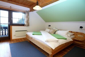 A wooden bed in a room with a sloped ceiling, a window with curtains, and a radiator. - Holiday apartment in Patergassen with sauna (Patergassen)