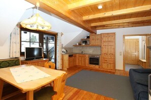 A cozy kitchen with wooden cabinets, a dining table, and a TV. - Holiday apartment in Patergassen with sauna (Patergassen)