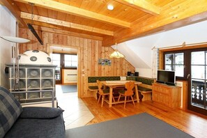 A cozy room with a wooden ceiling, a sofa, a dining table with chairs, a television, and a kitchen area with a window. - Holiday apartment in Patergassen with sauna (Patergassen)