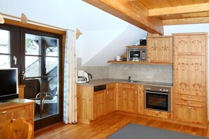 A kitchen with wooden cabinets, a microwave, an oven, and a dishwasher. - Holiday apartment in Patergassen with sauna (Patergassen)