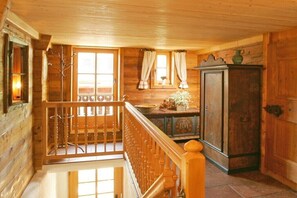 Ein Holzinnenraum mit einer Treppe, einem Holzkabinett und einem Fenster mit Vorhängen.