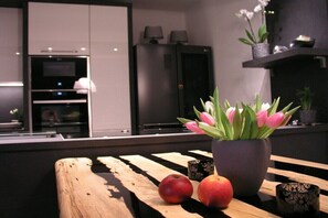 Una cocina moderna con una mesa de madera que muestra manzanas y una planta en maceta.