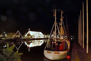 Ein Boot liegt in einer Marina vor Anker, mit freiem Blick auf das Wasser und einem Gebäude im Hintergrund.