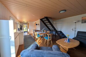 A compact living space with a kitchen, dining area, and a staircase leading to an upper level. - Holiday home in Wiek with swimming pool (Wiek)
