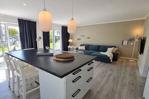 A modern kitchen with a central island, white cabinetry, and pendant lighting. - Holiday home with 2 bedrooms (Oldenburg in Holstein)