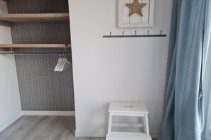 A room with a wardrobe, a small white table, a star decoration, and a blue curtain. - Holiday home with 2 bedrooms (Oldenburg in Holstein)