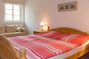A bedroom with a bed, a nightstand, a lamp, a window, and a wall-mounted picture. - Country house at Goor (Vilmnitz)