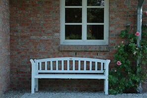 A white bench in front of a brick wall with a window and a rose bush. - Country house at Goor (Vilmnitz)