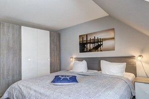 A modern hotel room with a bed, a painting, and a nightstand. - Holiday home with 1 bedroom (Trassenheide)