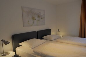 Ein Hotelzimmer mit Doppelbett, Nachttisch mit Lampe und einem an der Wand hängenden Kunstwerk.