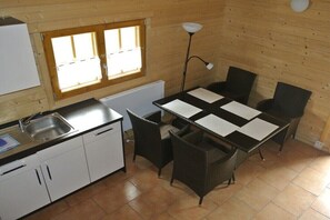Eine kleine Küche mit Spüle, weißen Schränken, einem Fenster und einem Tisch mit Stühlen.