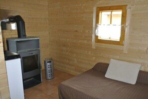 Ein kompakter Raum mit Holzvertäfelung, einem kleinen Fenster, einem Bett und einem Kamin.