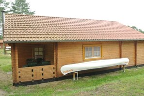 Eine Holzhütte mit Ziegeldach, einem Fenster und einer Bank vor der Tür.