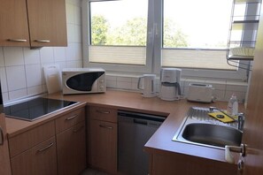 A kitchen with a microwave, coffee maker, toaster, dishwasher, and a sink with a yellow sponge. - "Lübeck Bay" in the TINTIN House (Scharbeutz)