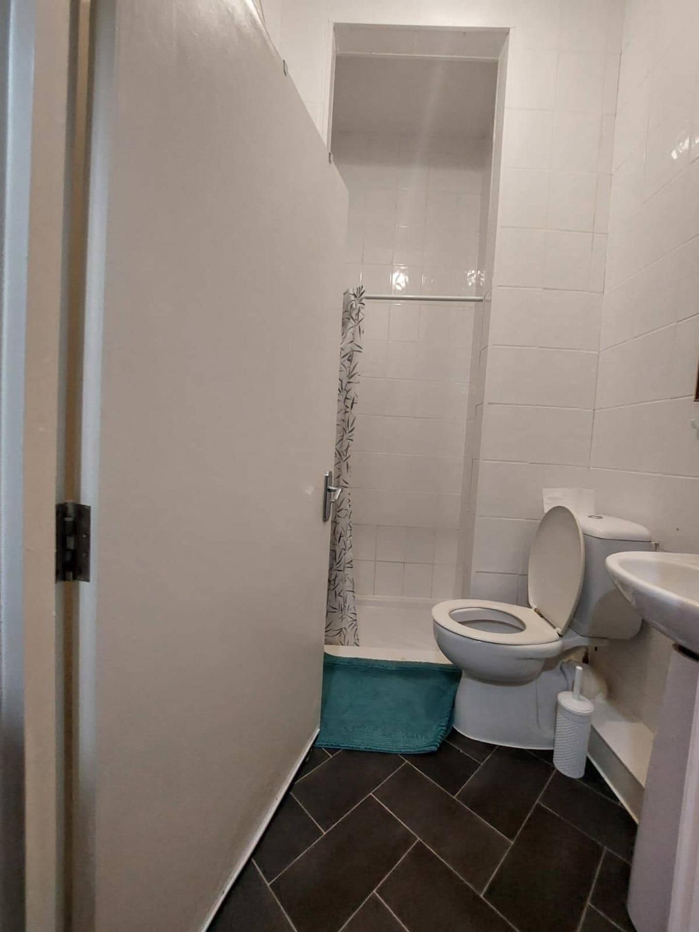 A small bathroom with a toilet, a shower stall, and a sink.