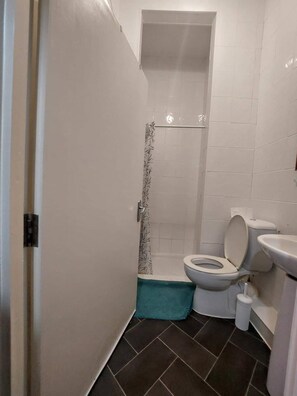 Un baño pequeño con inodoro, cabina de ducha y lavamanos.